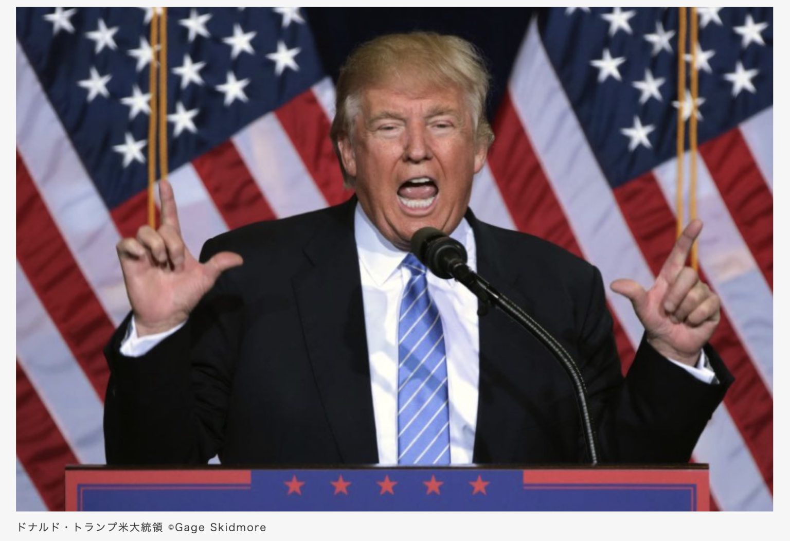 Donald Trump speaking in front of American flags.