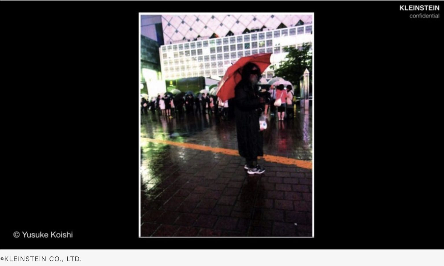 KLEINSTEIN slide showing a person in a black coat holding a red umbrella at night in Shibuya.